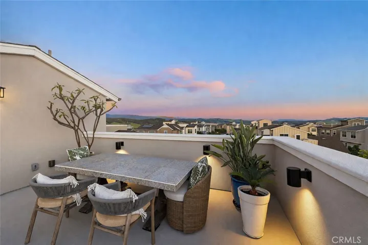Rooftop dining setting at dusk with glowing skies and hillside views.