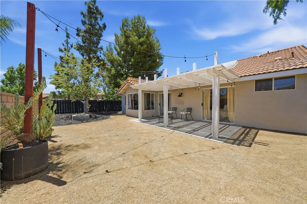 A backyard patio with a covered pergola provides the perfect setting for outdoor dining, relaxing, and entertaining.