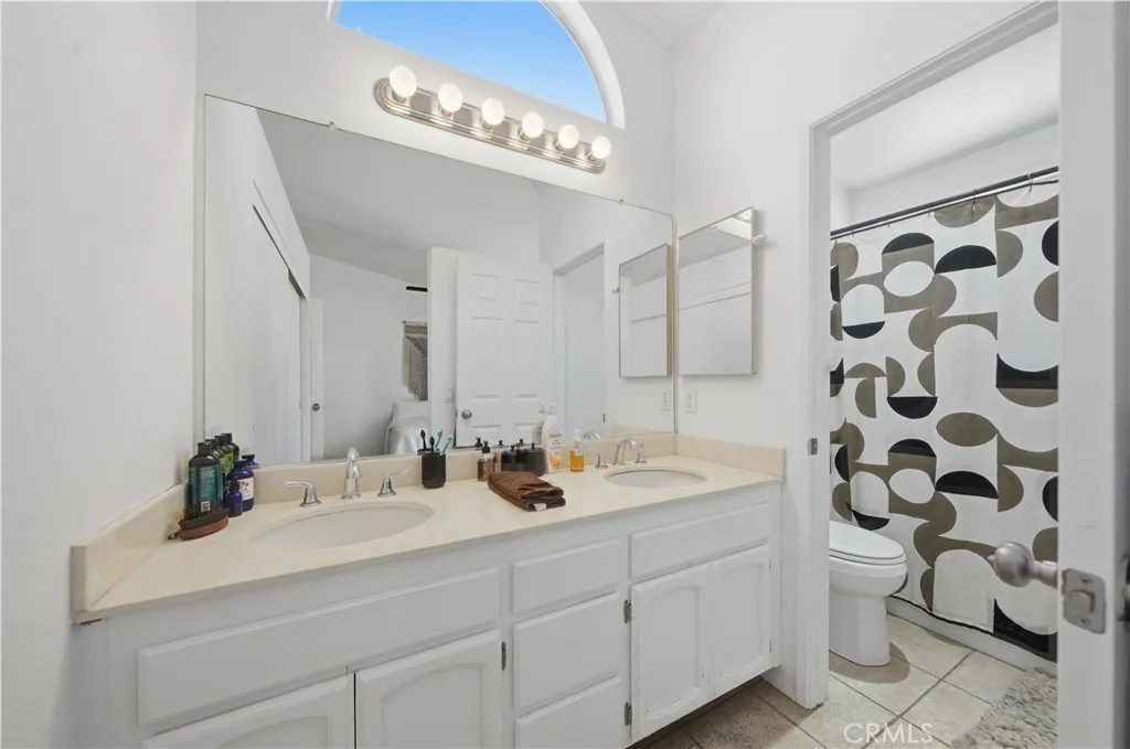 The primary bathroom features dual sinks, a large vanity, and a private shower-tub area, offering both comfort and functionality.