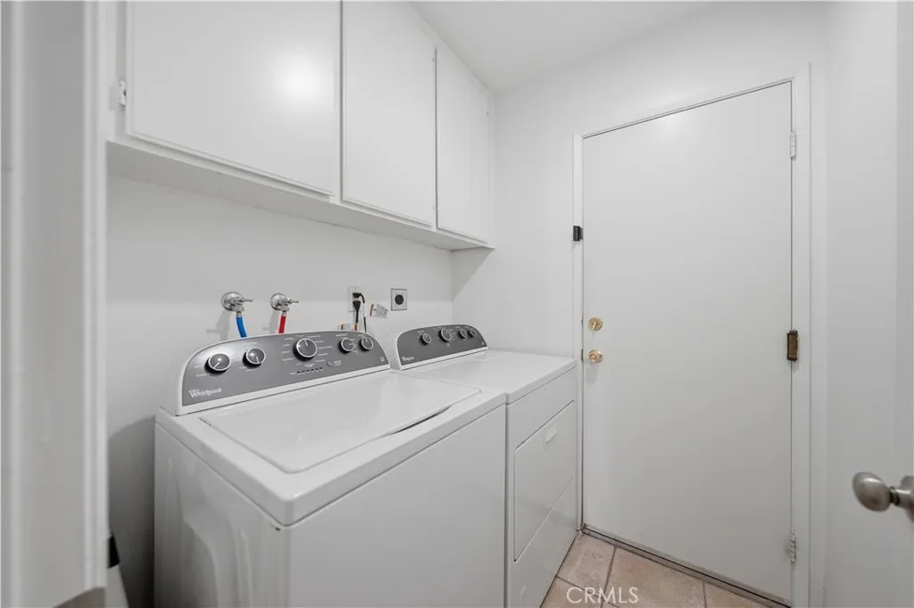 A dedicated laundry room with overhead cabinetry provides convenient storage and everyday functionality.