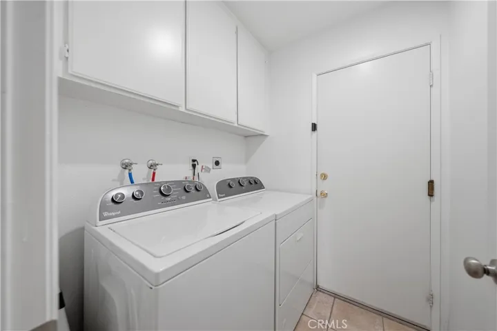 A dedicated laundry room with overhead cabinetry provides convenient storage and everyday functionality.