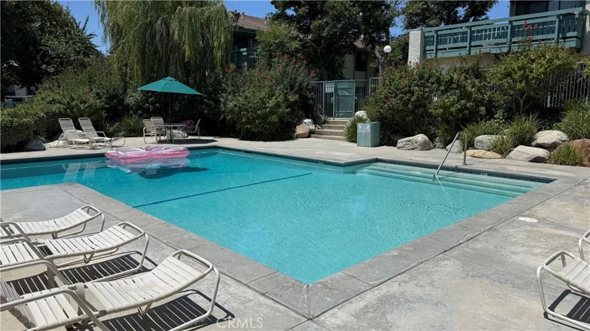 Spacious pool and lounging area and picnic tables.