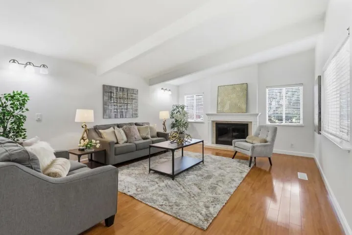Inviting living room featuring vaulted ceilings, hardwood floors, and a cozy fireplace.