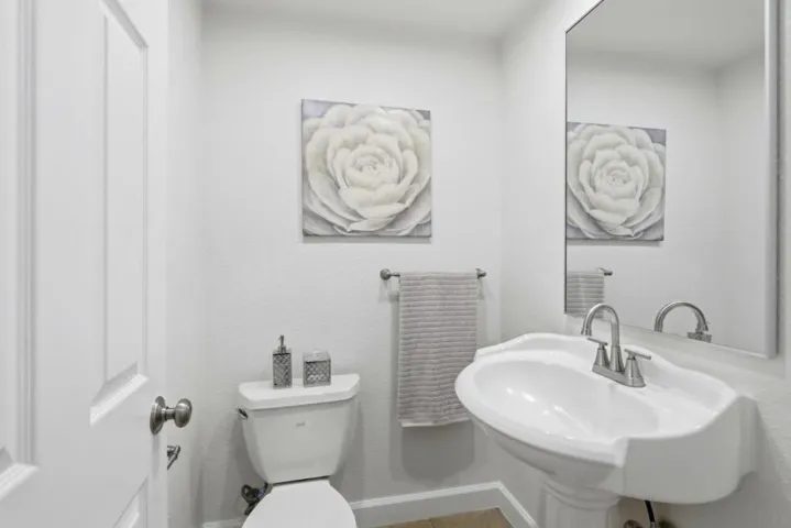 Bright guest powder room featuring a pedestal sink, large mirror, and clean contemporary finishes.