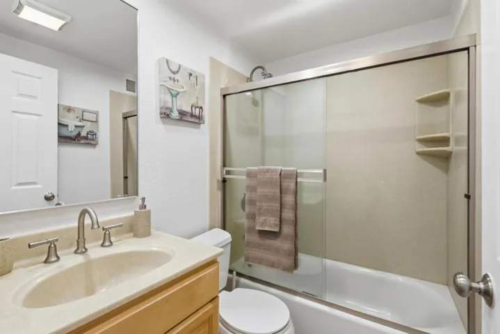 Full bathroom with updated fixtures, spacious vanity, and sliding glass shower enclosure.