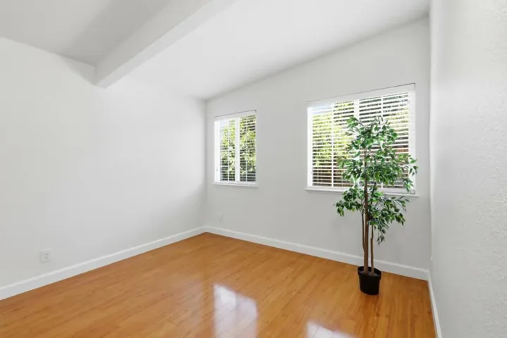 Bright bedroom with vaulted ceiling, large windows, and flexible space for family or guest