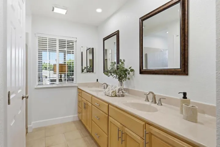 Spacious primary bathroom showcasing a dual-sink vanity, oversized mirrors, and ample cabinetry.