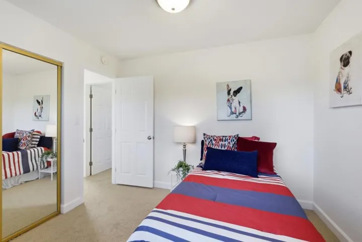 Bright upstairs bedroom with large window, mirrored closet doors, and flexible space.