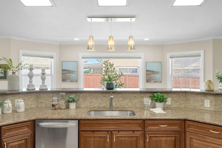 Granite sink wall with pendant lighting and panoramic windows looking out back.