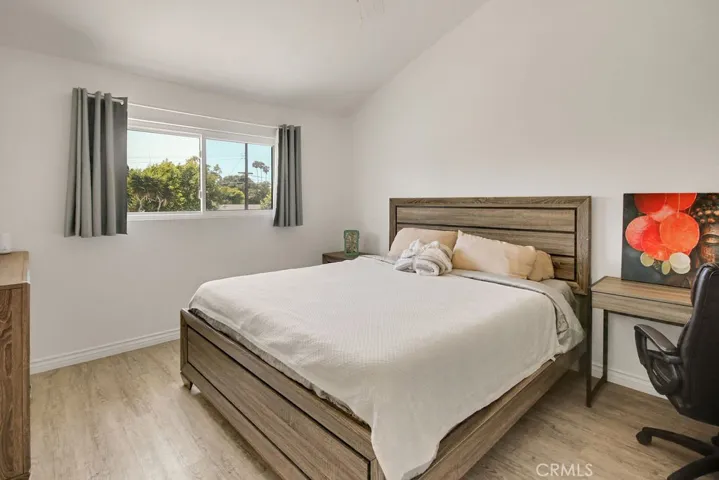 Spacious primary suite features high ceilings, luxury vinyl flooring, a custom walk-in closet, and peaceful neighborhood views.