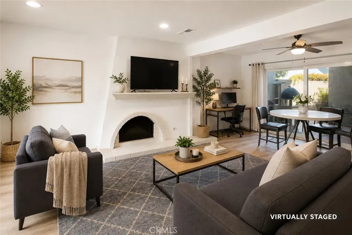Expansive living room with a cozy fireplace flows seamlessly to the private patio for easy indoor-outdoor living. Virtually staged to show potential.