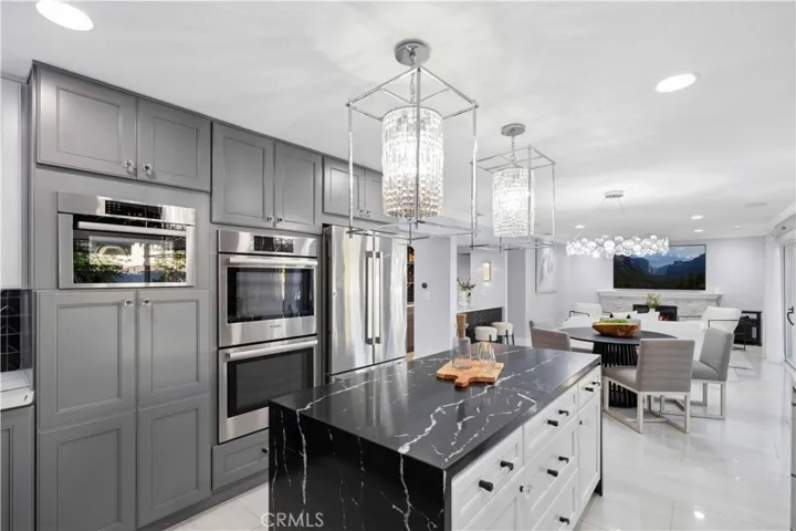 The remodeled kitchen boasts abundant cabinetry, a center island, and picturesque views of the private backyard retreat complete with a sparkling swimming pool and relaxing spa