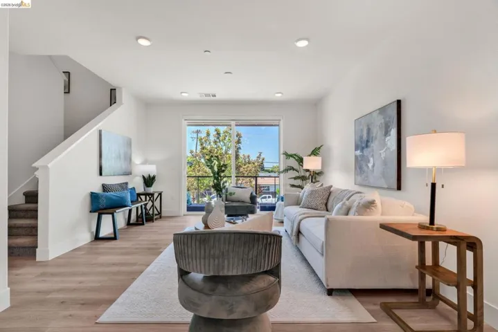 Expansive main living area featuring wood-finish flooring, a contemporary staircase with carpeted treads, and recessed ceiling lighting