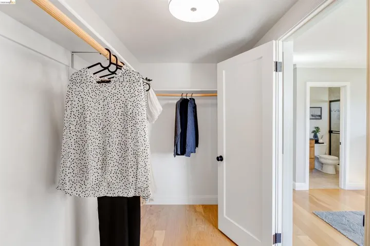 Walk-in closet featuring light wood-finish flooring, white walls, and a recessed ceiling light