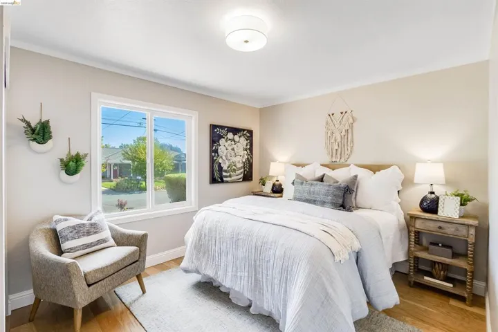 Bedroom with a large window, light wood-finish flooring, recessed ceiling lighting, crown molding, and neutral wall tones
