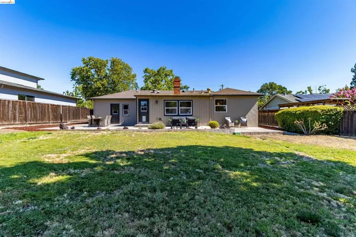Expansive backyard featuring a manicured lawn, a large concrete patio, and a privacy fence
