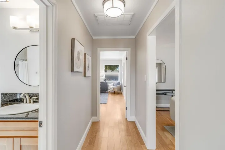 Hallway featuring light wood-finish flooring, light grey wall paint, and white trim