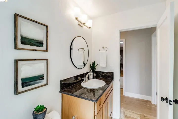 Bathroom vanity with a dark speckled countertop, undermount sink, and light wood-finish cabinetry