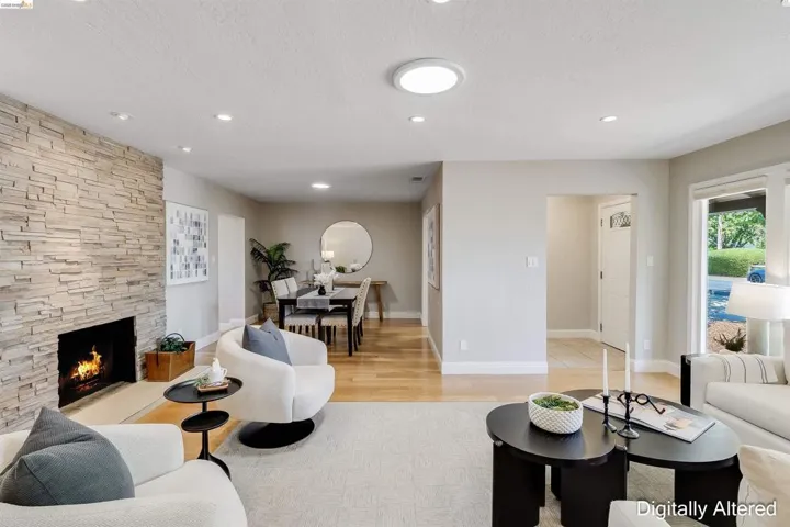 Living area featuring a floor-to-ceiling stacked stone fireplace, recessed lighting, and hardwood flooring extending into a dining space