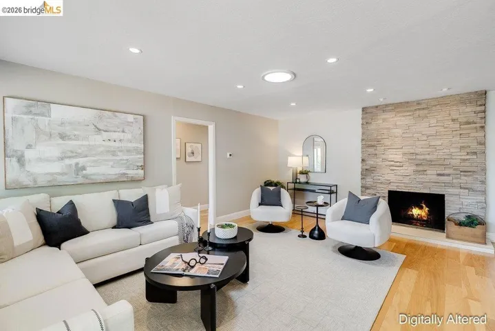 Living area featuring a floor-to-ceiling stacked stone fireplace, recessed lighting, a circular skylight, wood-finish flooring, and a neutral color palette