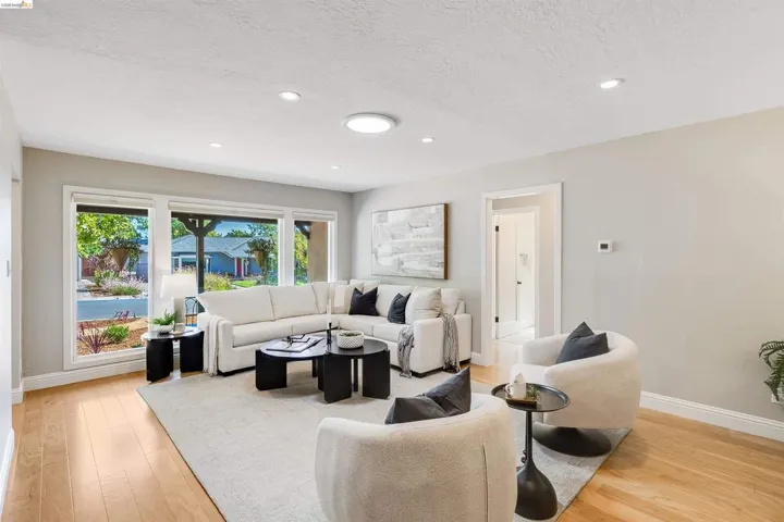 Spacious living area featuring large picture windows, wood-finish flooring, recessed lighting, and a neutral color palette
