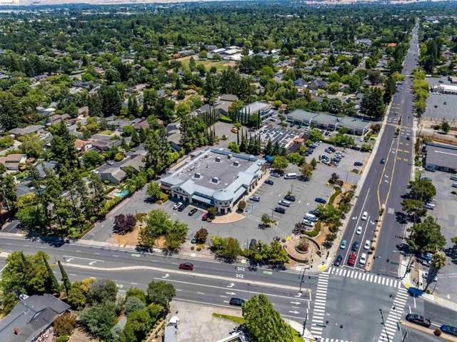 Commercial property featuring a large parking area, surrounding green landscaping, and multiple access points from a prominent thoroughfare