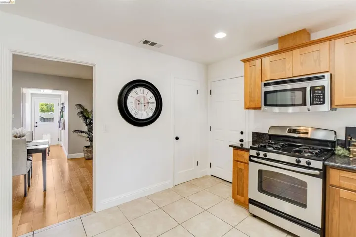 Kitchen featuring stainless steel range with overhead microwave, granite countertops, and wood cabinetry