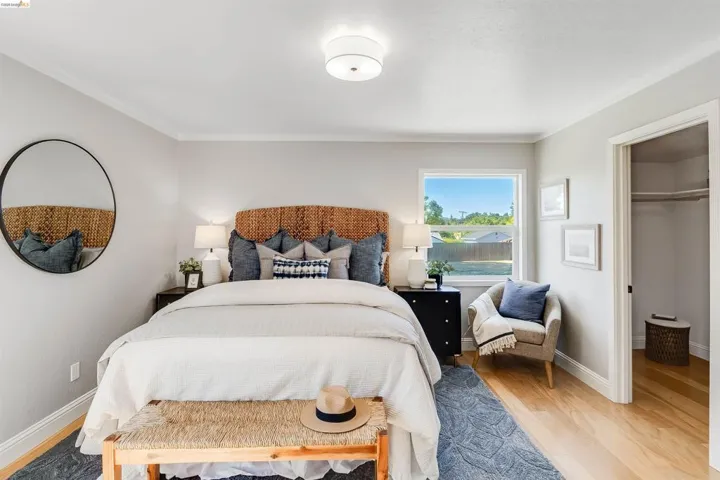 Bright bedroom with wood-finish flooring and a window offering outdoor scenery