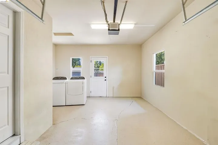 Spacious utility area featuring two windows, a side entry door, and overhead lighting
