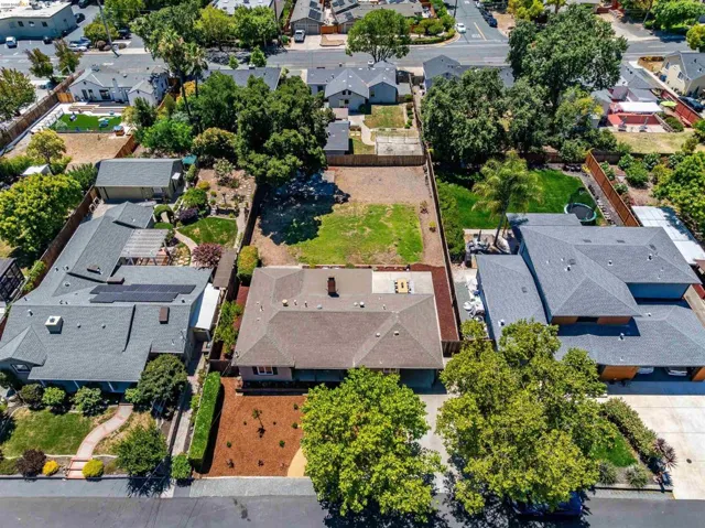 Expansive lot featuring a large grassy area, mature trees, and a paved driveway