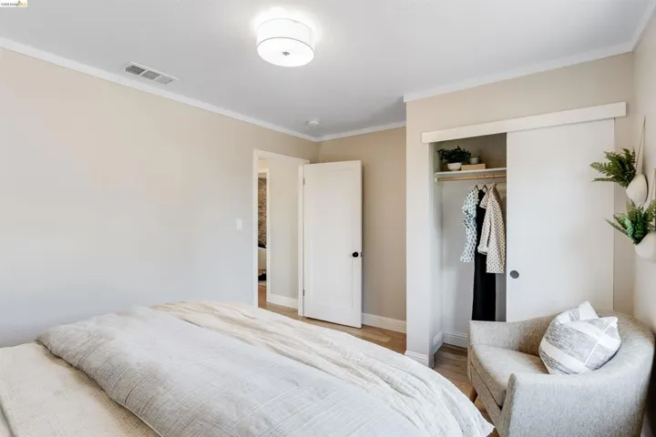 Bedroom featuring light wood-finish flooring, a flush-mount ceiling light fixture, and white crown molding