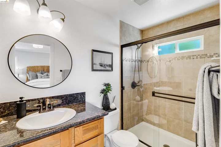 Bathroom featuring a glass-enclosed shower with tile surround, a built-in shower niche, and an upper transom window
