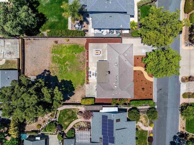 Aerial view showcasing a residential property with a shingled roof and a spacious backyard