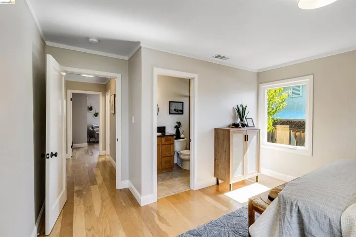 Light wood-finish flooring throughout, framed doorways, and a window with white trim