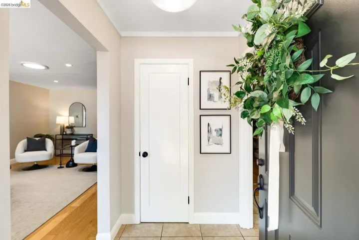 Entryway featuring tile flooring, a solid panel interior door with matte black hardware, and an arched doorway opening to a room with wood-finish flooring and recessed lighting