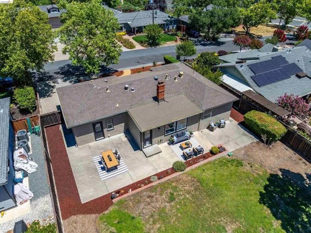 Expansive backyard featuring a concrete patio, a red bark landscape strip, and an adjacent lawn area