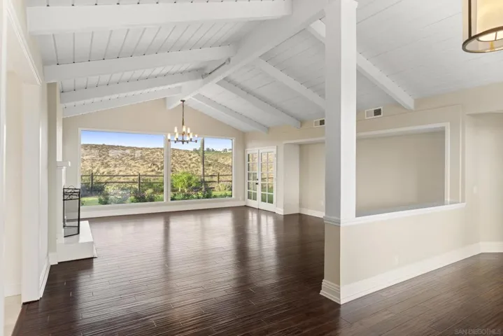 Formal living room with vaulted ceiling, rich wood flooring, fireplace, views