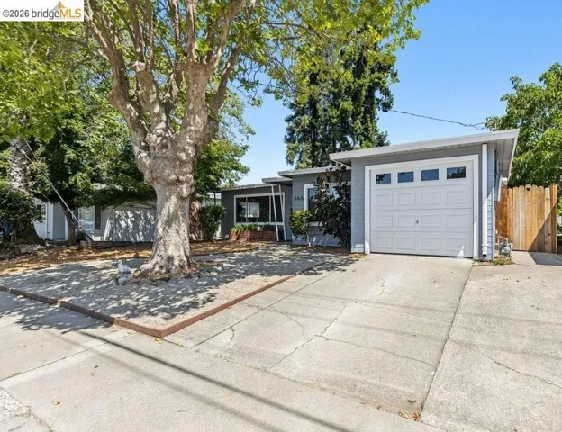 Single-story residence featuring a light gray exterior, a white panel garage door with windows, and a concrete driveway