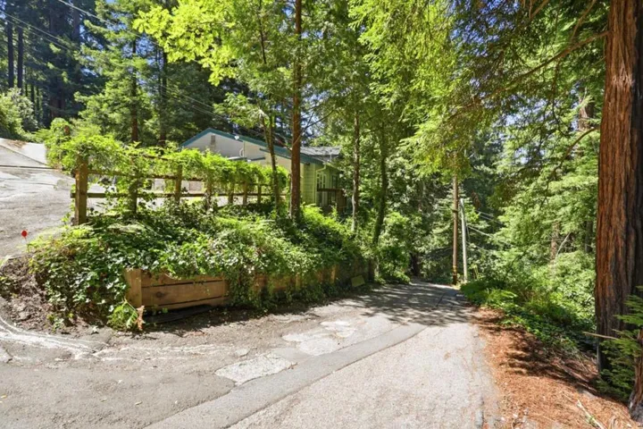 The road leading up to the house is on the right, parking area to left of fence
