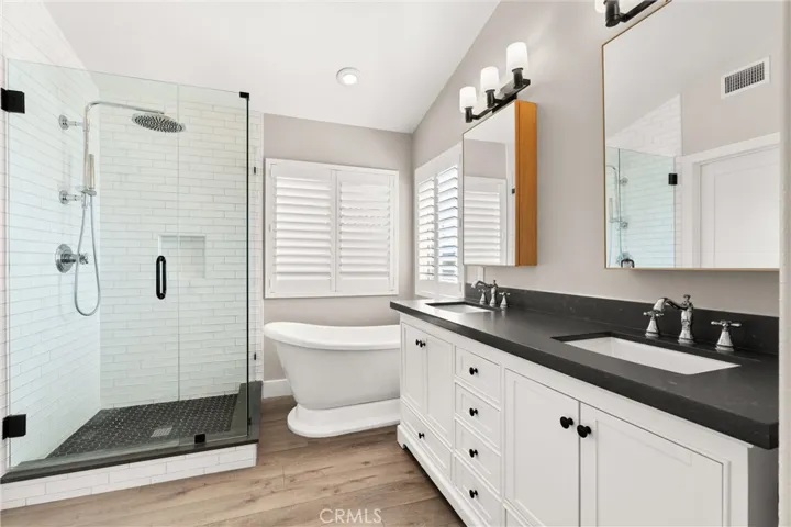 Spa-inspired primary bath featuring a freestanding soaking tub, dual vanities, and a frameless glass shower