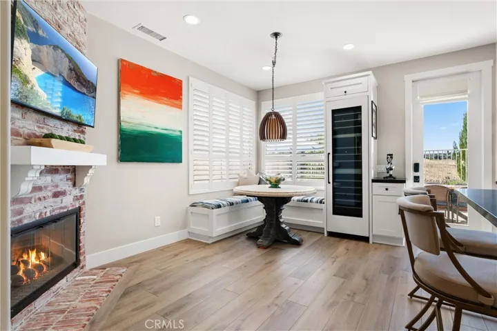 Dining area highlighted by a detailed brick fireplace, built-in banquette seating, and designer light fixture