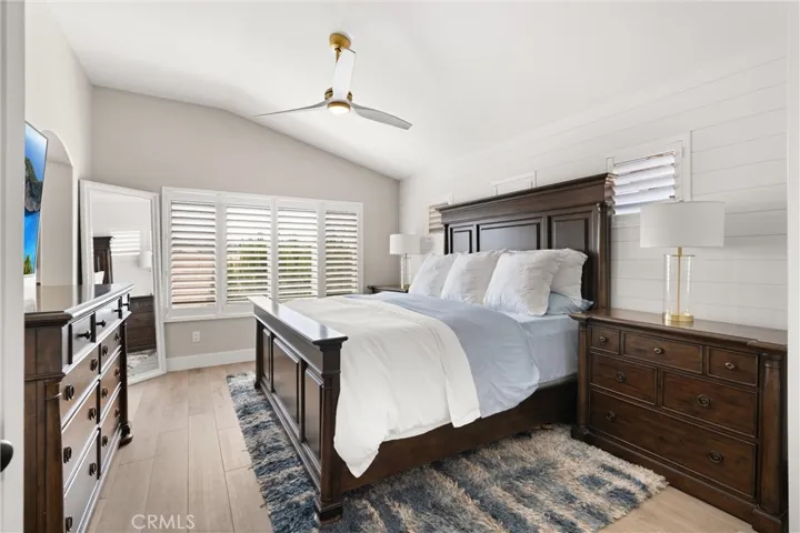 Elegant primary suite with vaulted ceilings, shiplap accents, and plantation shutters