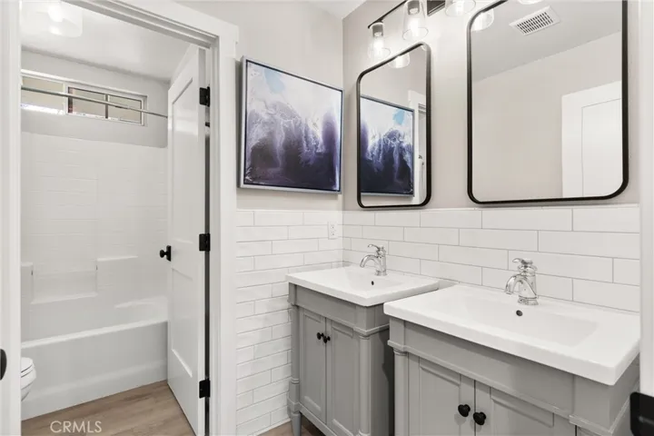Beautifully updated bathroom featuring dual sinks and subway tile accents