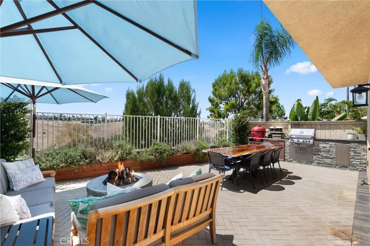 Private backyard retreat featuring herringbone pavers, a natural gas fire pit, and outdoor dining area