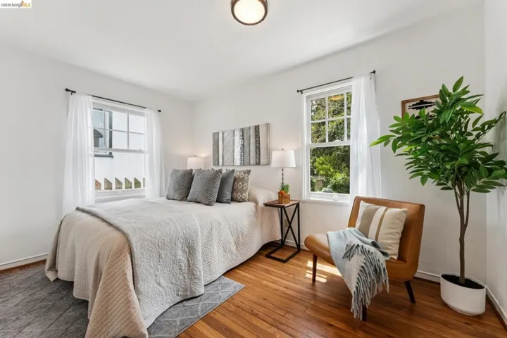 Bedroom featuring two large windows, wood-finish flooring, and a flush-mount ceiling light fixture