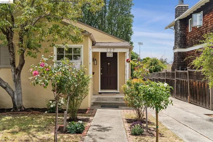 Cream stucco exterior with white trim windows and a dark brown entry door