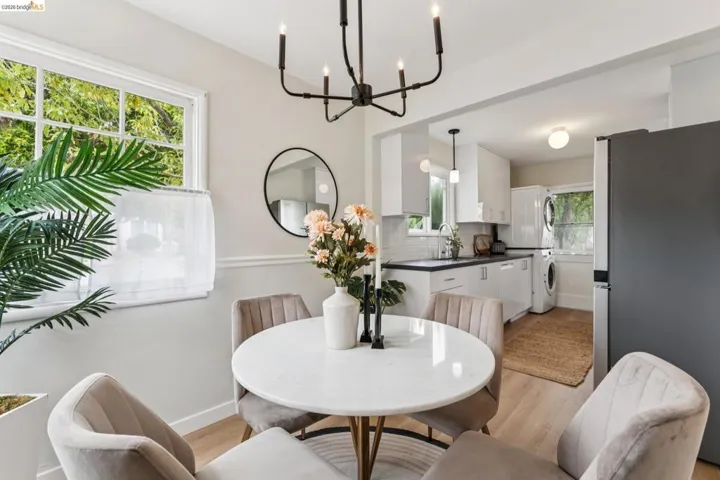 Dining area with a black chandelier, white baseboard molding, and a round wall mirror
