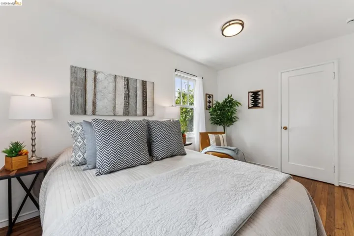 Hardwood flooring throughout this room features a bright window and a flush-mount ceiling light