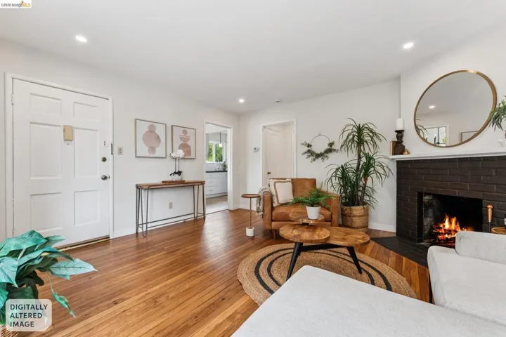 Expansive living area featuring warm wood flooring, a dark brick fireplace, and recessed lighting