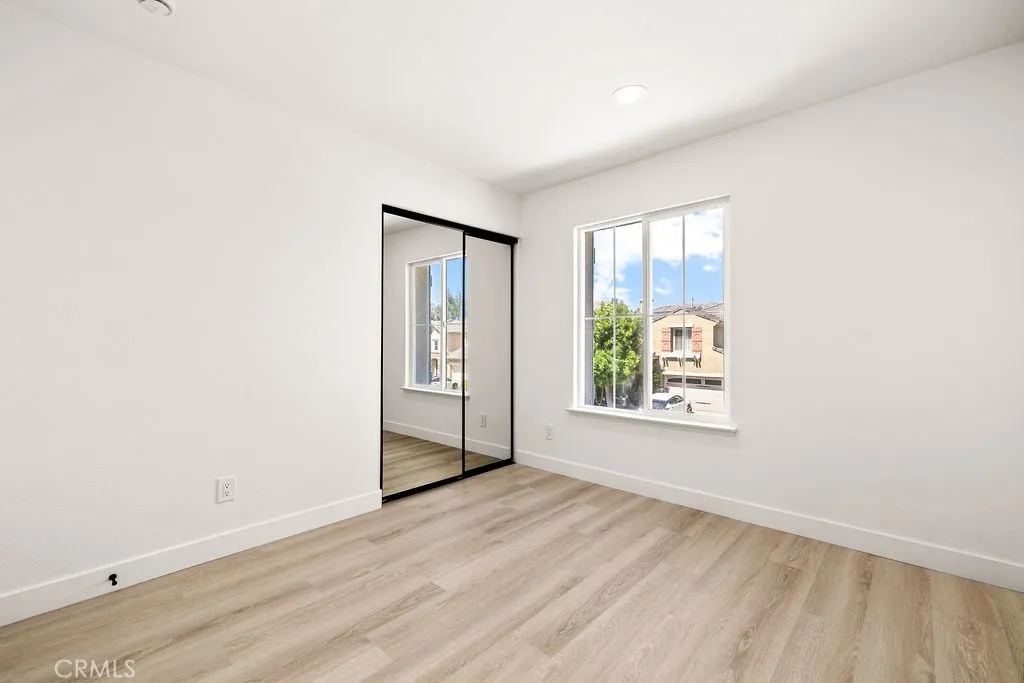 Secondary bedroom with mirrored closet doors and abundant natural light.